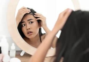 Woman Examining Hair In Mirror